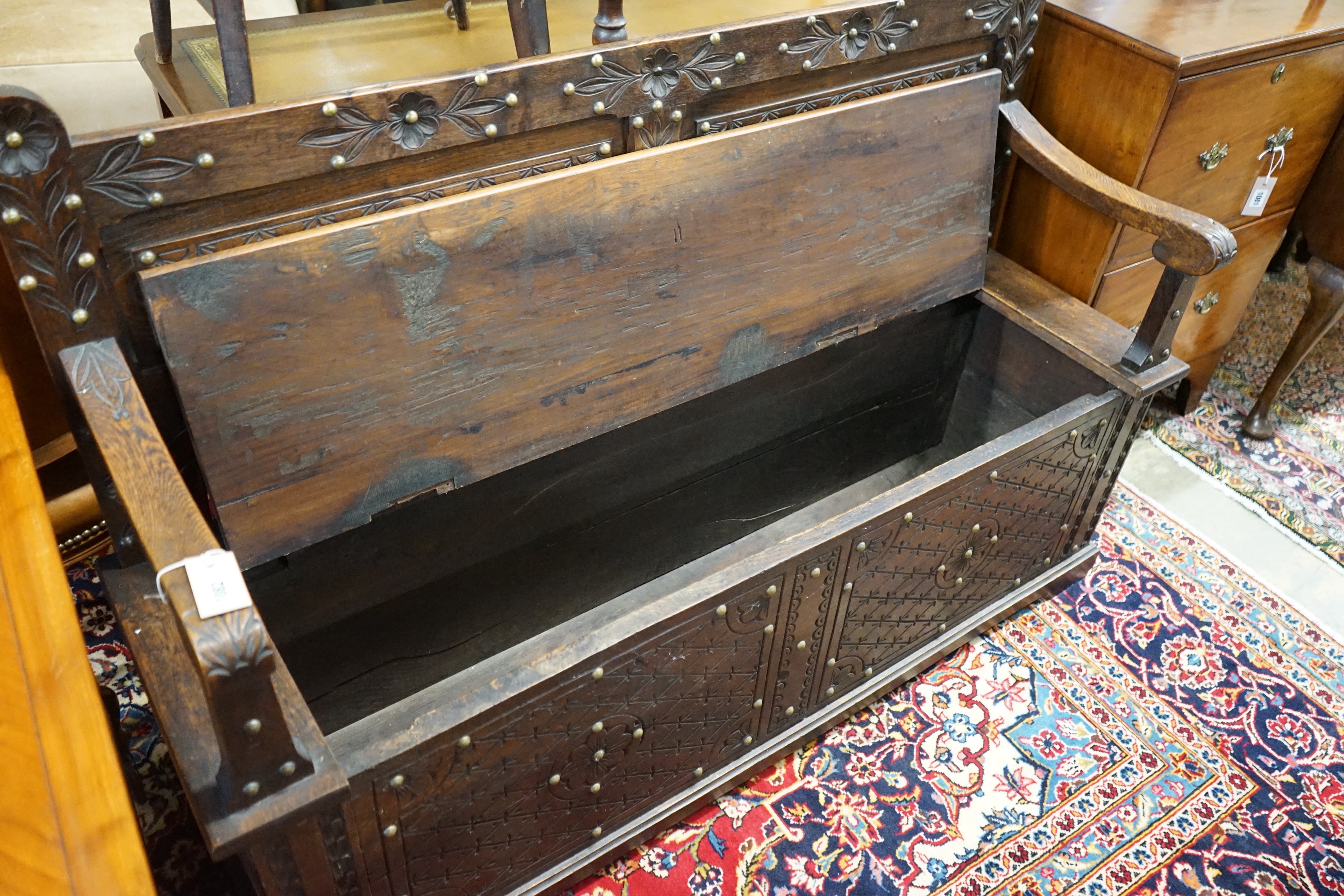 An 18th century style brass studded carved oak box seat settle, length 136cm, depth 40cm, height 93cm
